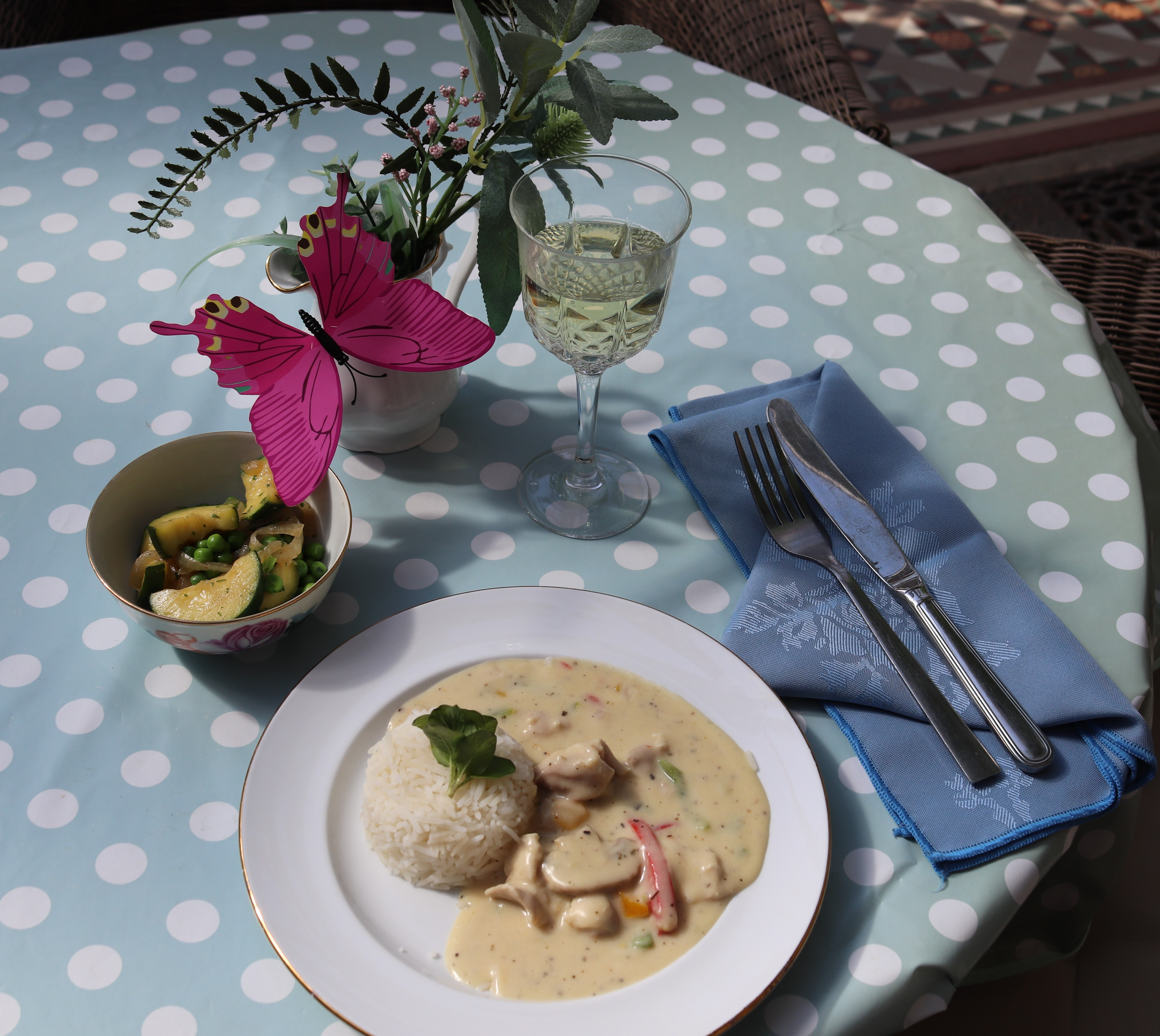 Chicken ala king dish on a table with a blue polka dot cloth and floral arrangement