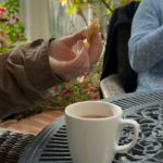 The image demonstrates 3 pictures of the facilities at Birchwood House: there is a plate of cake, and image of a hand holding a biscuit, and an image of outdoor seating